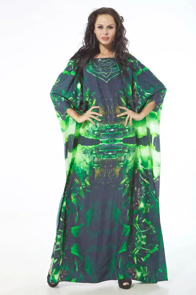 Model wearing a full-length cape-style Designer kaftan in Gotham-inspired green and black print with sleeve openings and Swarovski crystal embroidery at the neckline.